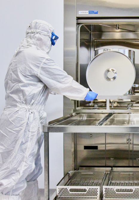 A worker in a white clean suit using a machine